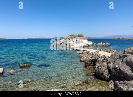 Chios, Agios Isidoros kleine Kirche, Griechenland. Traditionelle Architekturkapelle mit rotem Ziegeldach und Glockenturm auf Felsen, sonniger Sommertag Stockfoto