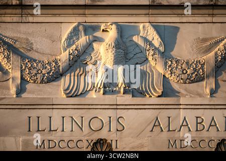 Lincoln Memorial Eagle Sculpture Washington DC // WASHINGTON DC — An eagle sculpture, part of the attic frieze on the southern facade of the Lincoln Memorial, catches the last golden rays of light right before sunset. The intricate marble carving features garlands and the names of the 48 states at the time of the memorial's 1922 dedication. Visible are ILLINOIS (MDCCCXVIII / 1818) and ALABAMA (MDCCCXIX / 1819). Dedicated to Abraham Lincoln, the 16th U.S. President, the monument is primarily constructed from white Colorado Yule marble. Stockfoto
