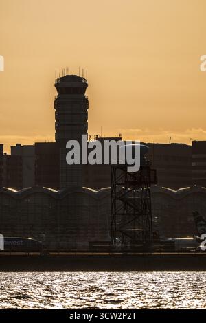 Reagan National Airport Air Traffic Control Tower in Sunset Washington DC // WASHINGTON DC – der Air Traffic Control Tower und das Terminal-Gebäude des Ronald Reagan Washington National Airport (DCA) sind vor der untergehenden Sonne umrahmt. Diese Aussicht wird vom Hains Point, einem Halbinsel-Park im East Potomac Park mit Blick auf den Potomac River, erfasst. Der Ronald Reagan Washington National Airport ist ein wichtiger Verkehrsknotenpunkt für die Metropolregion Washington D.C. und bietet hauptsächlich Inlandsflüge an. Der Flughafen liegt nur 8 km südlich von Downtown Washington D.C. Stockfoto