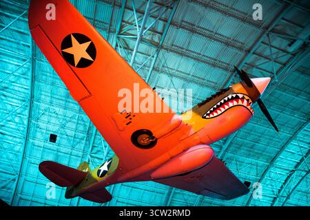 Curtiss P40 Warhawk Aircraft Smithsonian Air and Space Museum Chantilly Virginia // CHANTILLY, Virginia, Vereinigte Staaten — das haienhafte Curtiss P-40E Warhawk (Kittyhawk IA) Kampfflugzeug wird im Steven F. Udvar-Hazy Center ausgestellt. Das 1939 gebaute einmotorige, einsitzige Flugzeug wurde 1941 als Kittyhawk I nach Kanada geliefert. Es wurde 1975 restauriert, um eine P-40E der 75th Fighter Squadron, 23rd Fighter Group, 14th Air Force zu repräsentieren, die an die „Flying Tigers“-Flugzeuge aus dem Zweiten Weltkrieg erinnert. Das halbmonocoque-Ganzmetall misst 330 x 970 cm, 26 Stockfoto