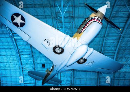 Curtiss P40E Warhawk Smithsonian Air and Space Museum Chantilly VA // CHANTILLY, Virginia — das Curtiss P-40E Warhawk mit seiner berühmten Haifischmaus-Nasenart und den US-Star-Insignien wird im Steven F. Udvar-Hazy Center ausgestellt. Dieses einmotorige, einsitzige Kampfflugzeug war ein erfolgreiches, vielseitiges Flugzeug in der ersten Hälfte des Zweiten Weltkriegs, das ursprünglich als Kittyhawk I nach Kanada geliefert wurde und bei der Royal Canadian Air Force diente. Es wurde 1975 restauriert, um ein Flugzeug der 75th Fighter Squadron, 23rd Fighter Group, 14th Air Force, bei der Smithsonian National Air and Space zu repräsentieren Stockfoto