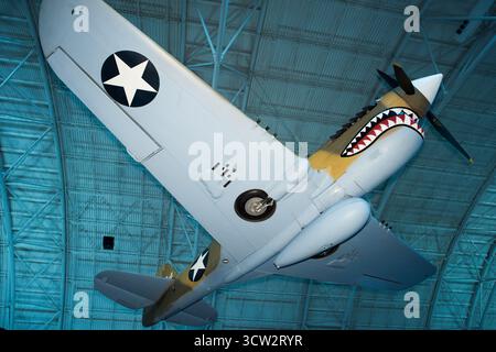 Curtiss P40E Warhawk Kittyhawk IA Smithsonian Air and Space Museum CHANTILLY VA // CHANTILLY, VIRGINIA, VEREINIGTE STAATEN — das Kampfflugzeug Curtiss P-40E Warhawk (Kittyhawk IA) mit seiner legendären Nasenart „Haifischmaus“ wird im Steven F. Udvar-Hazy Center ausgestellt. Dieses vielseitige Kampfflugzeug aus dem Zweiten Weltkrieg ist bekannt für seinen Dienst, insbesondere bei den „Flying Tigers“ in China. Das 1941 von Curtiss-Wright gebaute Flugzeug diente als Kittyhawk I bei der Royal Canadian Air Force. Es wurde 1975 restauriert, um ein Flugzeug der 75th Fighter Squadron, 23rd Fighter Group, 14th Air zu repräsentieren Stockfoto