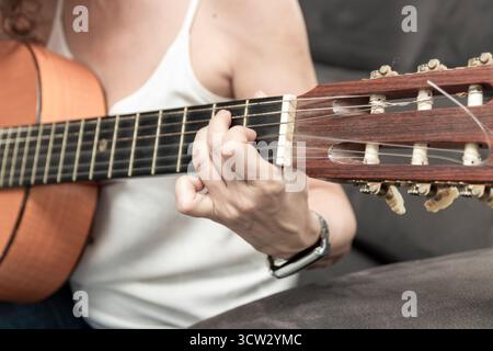 Frauenhände drücken Griffbrettsaiten der klassischen Gitarre und kreieren Musik Stockfoto