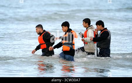 Menschen, die als Migranten gelten, waten durch das Meer, um an Bord eines kleinen Bootes in Gravelines, Frankreich, zu gehen. Bilddatum: Donnerstag, 9. Oktober 2025. Stockfoto