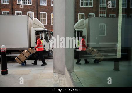 Der Postarbeiter von Royal Mail schiebt einen Wagen mit Kisten entlang der Chancery Lane in Zentral-London, England, Großbritannien Stockfoto