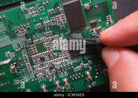 Wartung elektronischer Systeme. Reinigen des Staubs auf den oberflächlichen Halbleiterkomponenten digitaler Geräte. Stockfoto