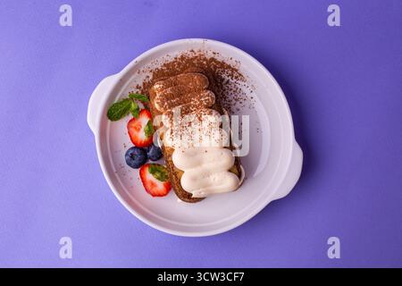 Tiramisu mit Beeren - Blick von oben auf violettem Hintergrund, klassisch in eleganter Beschichtung Stockfoto