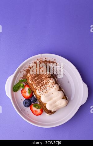 Tiramisu mit Beeren - Blick von oben auf violettem Hintergrund, klassisch in eleganter Beschichtung Stockfoto