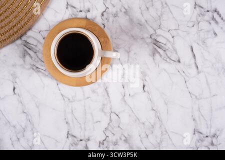 Ein minimalistischer und auffälliger flacher Lay fängt eine Tasse tiefschwarzen Kaffees auf, zentriert auf einem luxuriösen Marmorhintergrund. Dies direkt, an Stockfoto