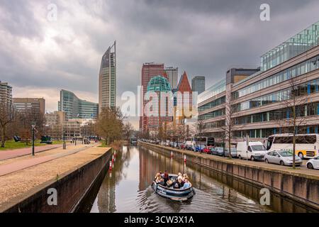 Blick auf den Wasserkanal und die Wolkenkratzer in den Haag, Niederlande. Die Leute machen eine Bootsfahrt durch die Kanäle von den Haag Stockfoto