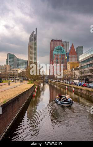Blick auf den Wasserkanal und die Wolkenkratzer in den Haag, Niederlande. Die Leute machen eine Bootsfahrt durch die Kanäle von den Haag Stockfoto