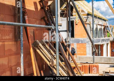 Die Arbeiter bereiten sich auf den Bau eines Standorts vor, dessen Gerüste und Ziegelsteine unter einem klaren blauen Himmel sichtbar sind und die fortwährende Aktivität und den Fortschritt zeigen. Stockfoto