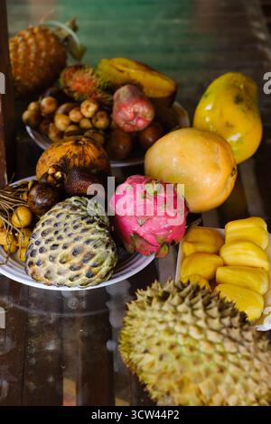 Auf einem lokalen Markt in Südostasien werden verschiedene exotische Früchte auf Tellern serviert. Stockfoto