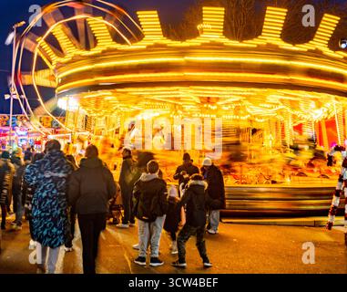 Worcestershire, England-29. November 2024: Mitglieder des Publikums beobachten und genießen eine hell erleuchtete Reittour mit Karussellpferden und Big Wheel Spinnin Stockfoto