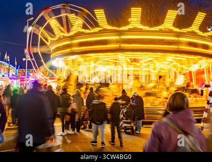 Worcestershire, England-29. November 2024: Mitglieder des Publikums beobachten und genießen eine hell erleuchtete Reittour mit Karussellpferden und Big Wheel Spinnin Stockfoto