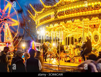 Worcestershire, England-29. November 2024: Mitglieder des Publikums beobachten und genießen eine hell erleuchtete Reittour mit Karussellpferden und Big Wheel Spinnin Stockfoto