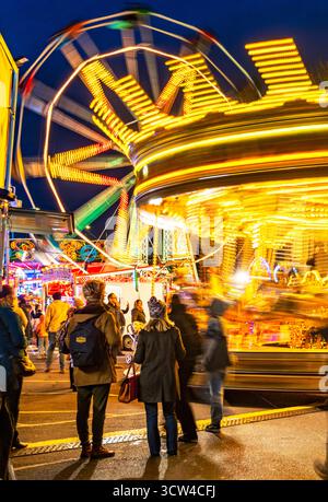 Worcestershire, England-29. November 2024: Mitglieder des Publikums beobachten und genießen eine hell erleuchtete Reittour mit Karussellpferden und Big Wheel Spinnin Stockfoto