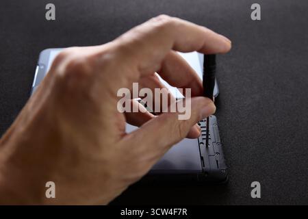 Nahaufnahme einer Hand, die kleine Komponenten in einem Smartphone mithilfe von Präzisionswerkzeugen justiert. Das Foto zeigt die detaillierten Arbeiten, die mit dem Mobilgerät verbunden sind Stockfoto