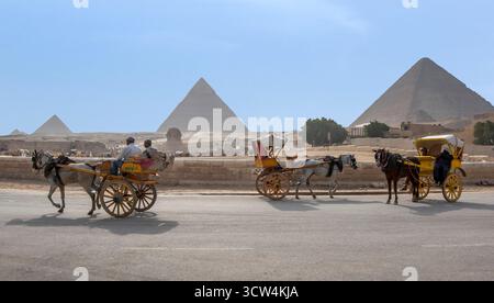 KAIRO, ÄGYPTEN - 4. MAI 2013: Pferdewagen sammeln sich vor den Pyramiden von Gizeh und der Sphinx auf dem Gizeh-Plateau in Kairo in Ägypten. Stockfoto