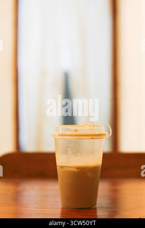 Nahaufnahme einer Plastiktasse Kaffee Latte Eis zum Mitnehmen auf dem Kaffeetisch Stockfoto