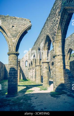Die Abtei Saint-Mathieu de Fine-Terre in der Bretagne, Frankreich. Das Innere der gotischen Ruine im Sonnenlicht zeigt hohe Bögen und verwitterte Steinsäulen. Stockfoto