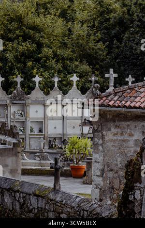 Ein galizischer Dorffriedhof aus Stein mit Kreuzen und einer Mausoleum-Mauer gegenüber Bäumen. Stockfoto