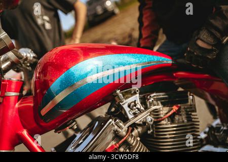 Speziell gefertigtes Motorrad mit einem leuchtend roten Tanktank und einem glitzernden blauen und silbernen Glitzerstreifen, der die Leidenschaft für Biker und Biker widerspiegelt Stockfoto