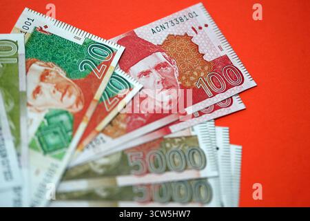 Pakistanische Rupien Banknoten auf rotem Hintergrund. Die aktuellen pakistanischen Geldrechnungen liegen in großer Höhe auf dem Tisch. Das Konzept des Geschäfts und der Investitionen in Pakistan Stockfoto