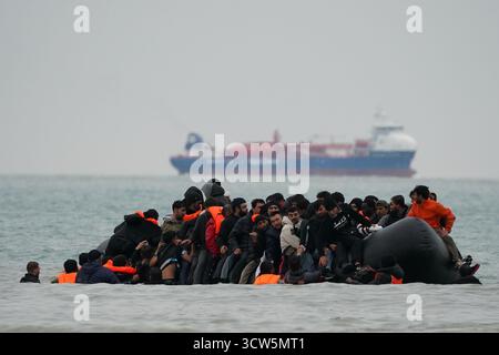 Menschen, die als Migranten gelten, waten ins Meer, um an Bord eines kleinen Bootes in Gravelines, Frankreich, zu gehen. Bilddatum: Freitag, 10. Oktober 2025. Stockfoto