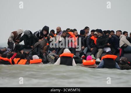 Menschen, die als Migranten gelten, waten ins Meer, um an Bord eines kleinen Bootes in Gravelines, Frankreich, zu gehen. Bilddatum: Freitag, 10. Oktober 2025. Stockfoto