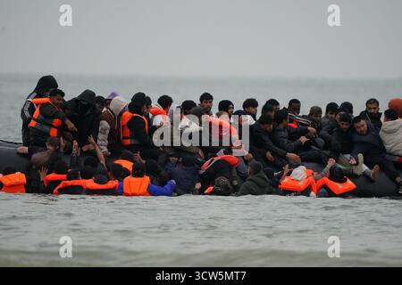 Menschen, die als Migranten gelten, waten ins Meer, um an Bord eines kleinen Bootes in Gravelines, Frankreich, zu gehen. Bilddatum: Freitag, 10. Oktober 2025. Stockfoto