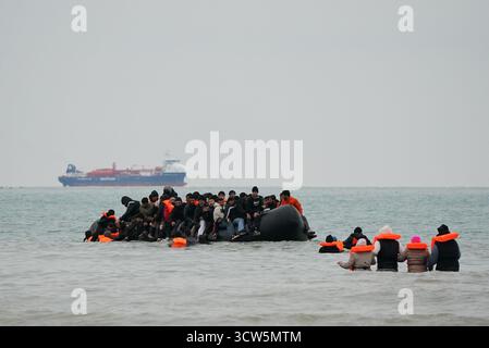 Menschen, die als Migranten gelten, waten ins Meer, um an Bord eines kleinen Bootes in Gravelines, Frankreich, zu gehen. Bilddatum: Freitag, 10. Oktober 2025. Stockfoto