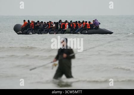 Menschen, die als Migranten gelten, waten ins Meer, um an Bord eines kleinen Bootes in Gravelines, Frankreich, zu gehen. Bilddatum: Freitag, 10. Oktober 2025. Stockfoto