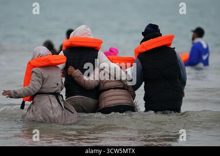 Menschen, die als Migranten gelten, waten ins Meer, um an Bord eines kleinen Bootes in Gravelines, Frankreich, zu gehen. Bilddatum: Freitag, 10. Oktober 2025. Stockfoto