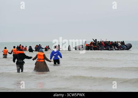 Menschen, die als Migranten gelten, waten ins Meer, um an Bord eines kleinen Bootes in Gravelines, Frankreich, zu gehen. Bilddatum: Freitag, 10. Oktober 2025. Stockfoto
