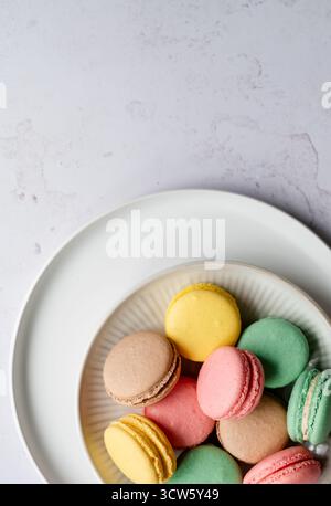 Draufsicht Nahaufnahme einer Platte mit bunten Macarons auf weißem Hintergrund. Stockfoto