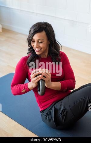 Lächelnde Frau beim Core-Workout mit Kettlebell Stockfoto