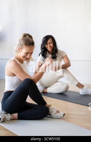 Glückliche Frauen, die sich nach einem Workout zusammen dehnen Stockfoto