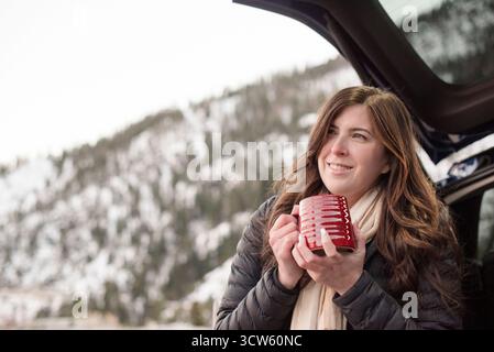 Frau schlürft heißen Kakao in den schneebedeckten Tahoe Bergen und genießt die Aussicht Stockfoto