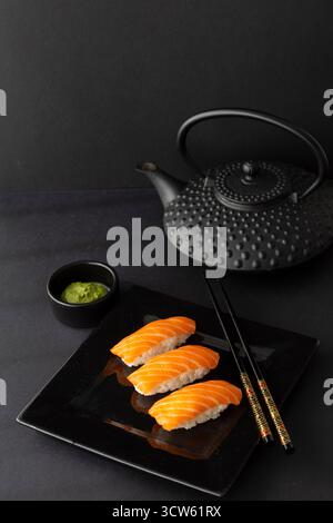 Blick von oben auf Lachsnigiri mit Wasabi und Teekanne Stockfoto