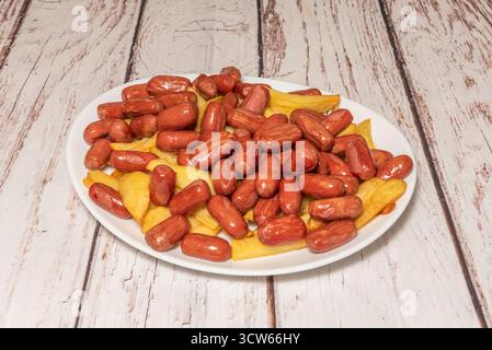 Würstchen in hausgemachter Tomatensauce mit Zwiebeln, Paprika und Gewürzen, begleitet von weißem Reis und gebratenen Kochbananen Stockfoto