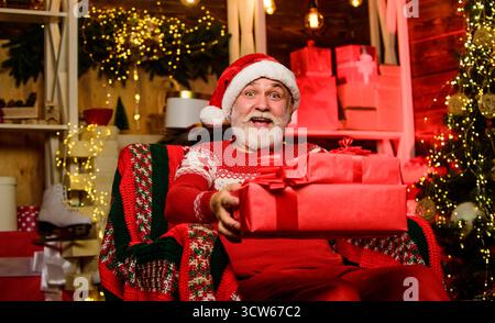 Online-Shop. Bärtiger Mann geht einkaufen. weihnachtsgeschenke. Geschenke bei Tannenbaum. Frohe weihnachten. Shopping im Winter. Partyfeier. Geschenke von Stockfoto