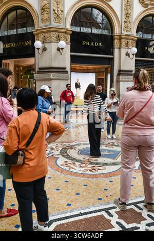 Junge Frau, die das traditionelle Glücksritual auf dem Stiermosaikboden in der Galleria Vittorio Emanuele II, Mailand, Lombardei, Italien vorführt Stockfoto
