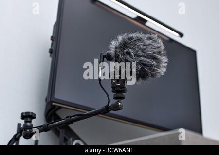 Schwarzer, professioneller Mikrofonständer für die Aufnahme von Stimmen in Online-Podcasts im Heimstudio. Flauschiges Mikrofon und Computer auf dem Tisch Stockfoto