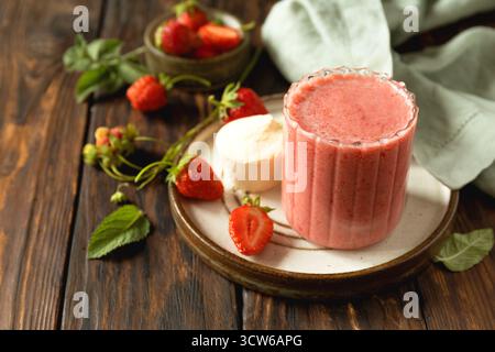 Frischer Erdbeerprotein-Smoothie auf einem Holztisch mit frischen Erdbeeren und einem Proteinpulver. Kopierbereich. Stockfoto