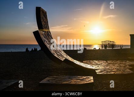 Brighton UK 9 Oktober 2025 - Besucher genießen einen wunderschönen Sonnenuntergang über Brighton Beach und dem West Pier nach einem weiteren warmen Tag an der Südküste . Brighton UK 9 Oktober 2025 - Besucher genießen einen wunderschönen Sonnenuntergang über Brighton Beach Passacaglia Skulptur und West Pier nach einem weiteren warmen Tag entlang der Südküste . Passacaglia ist eine riesige, gekrümmte abstrakte Skulptur von Charles Hadcock: Credit Simon Dack / Alamy Live News : Credit Simon Dack / Alamy Live News Stockfoto