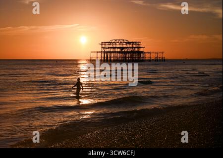 Brighton UK 9. Oktober 2025 - Ein Meeresschwimmer genießt einen wunderschönen Sonnenuntergang über Brighton Beach und dem West Pier nach einem weiteren warmen Tag an der Südküste : Credit Simon Dack / Alamy Live News Stockfoto
