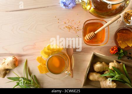 Frisch zubereiteter Ingwer- und Honigaufguss auf einer Holzbank mit Ingwerwurzeln, Gläsern mit Honigblumen und Dekoration. Draufsicht. Stockfoto