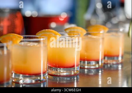 Nahaufnahme von Tequila-Sonnenaufgang oder tropischen Cocktails. Erfrischende alkoholische Getränke mit Gradienten und Zitrusfrüchten in Glasgläsern Stockfoto
