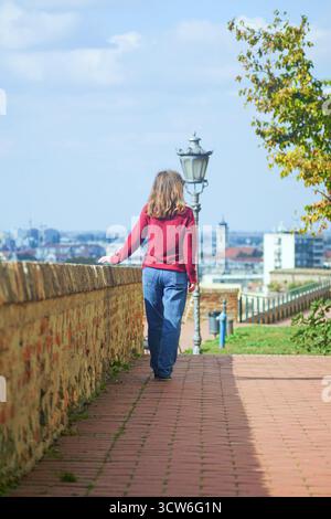 Frau, die entlang der Verteidigungsmauer in der Festung Petrovaradin läuft. Konzepte für einen europäischen Städtetrip, historische Architekturbesichtigung und Wochenendausflug Stockfoto